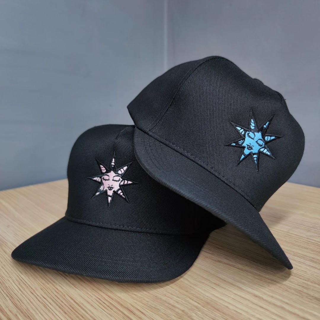 Two black baseball caps with embroidered star designs, one pink and one blue.