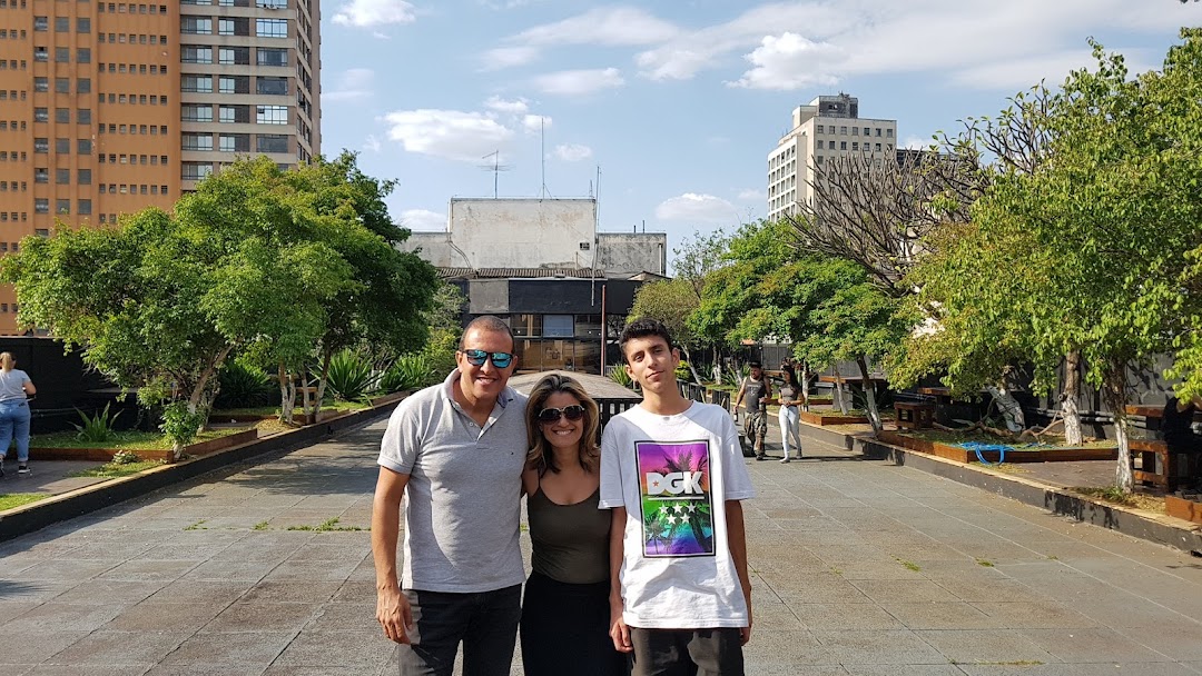 A family poses for a photo outdoors with trees and buildings in the background.