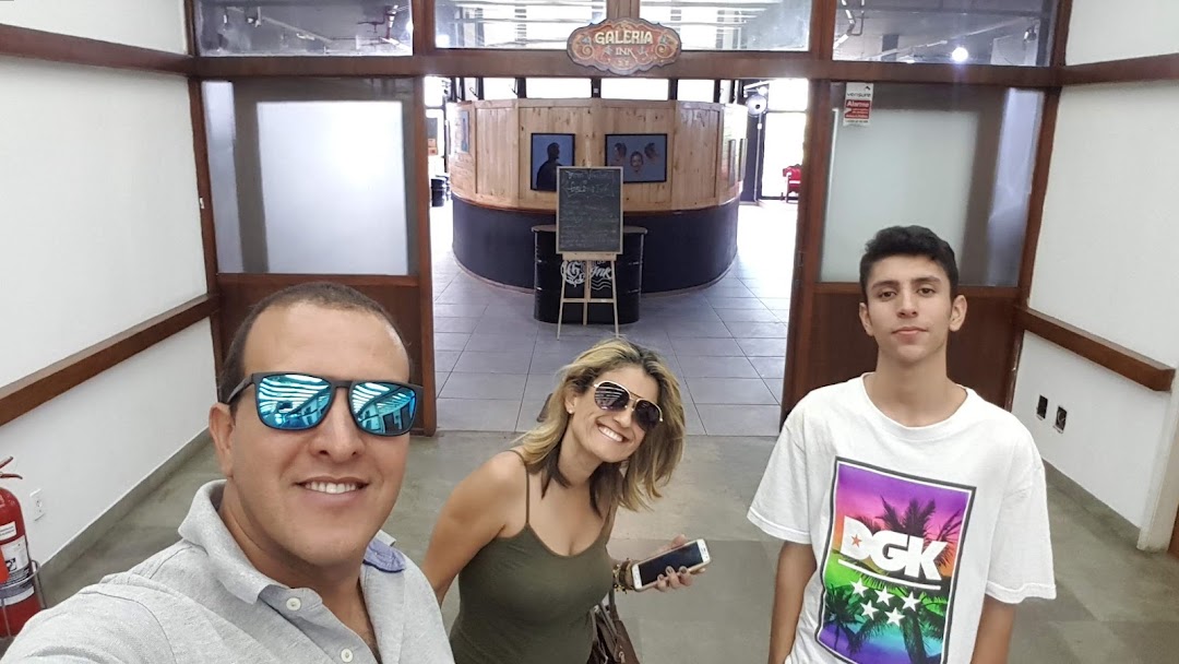 A family poses for a selfie in front of a tattoo studio entrance.