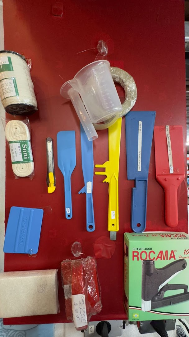 A collection of tools including spatulas, a utility knife, measuring cup, tape, and a stapler.