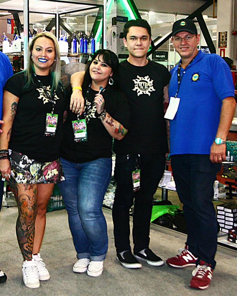 Four people posing for a photo, likely staff at a piercing or tattoo convention.
