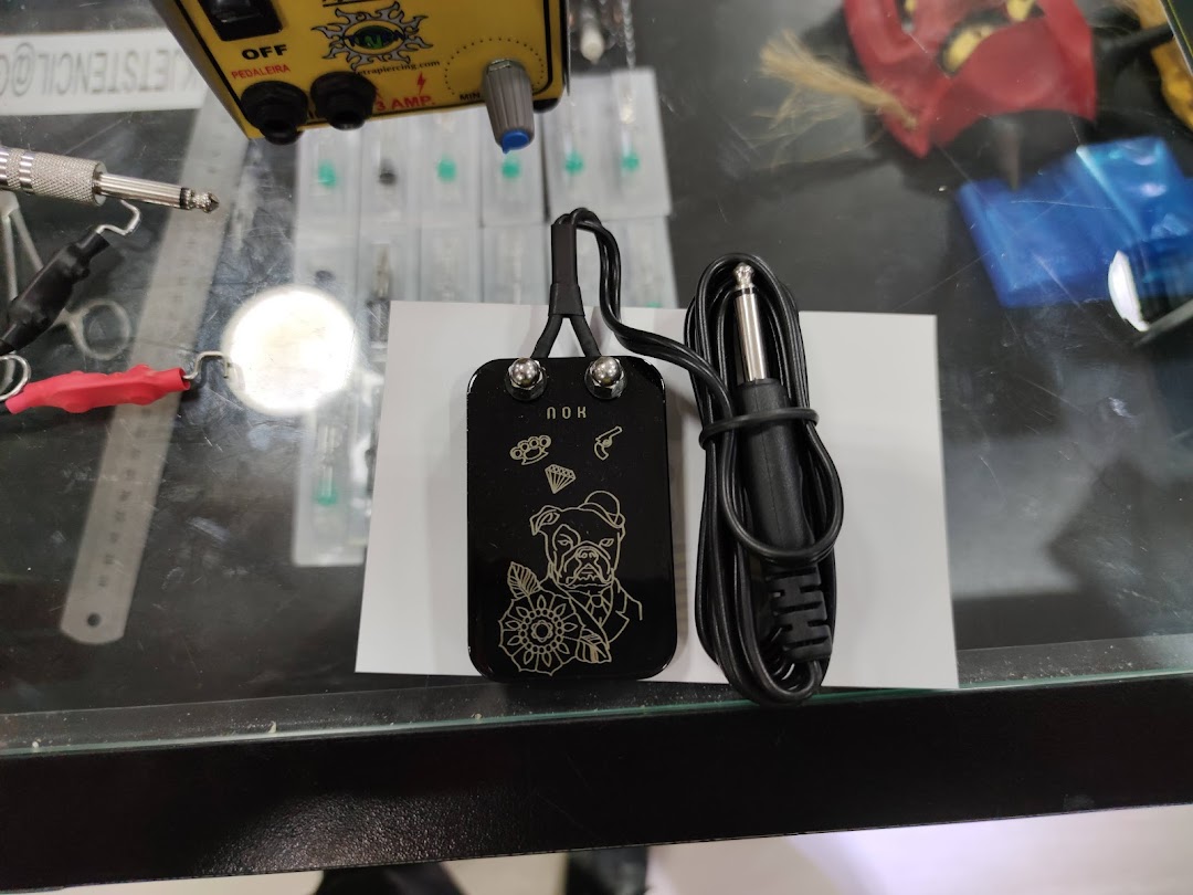 Close-up of a tattoo machine foot pedal with a bulldog design and tattoo needles.