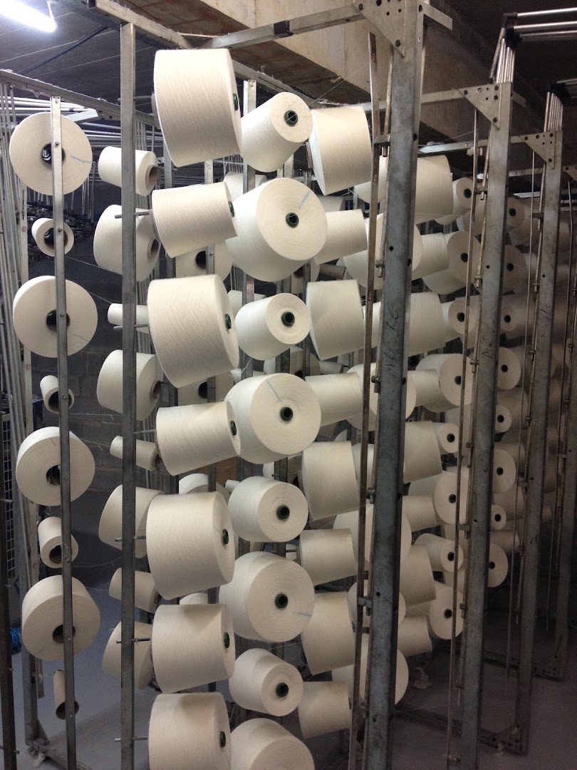 A large industrial rack filled with many spools of white yarn.