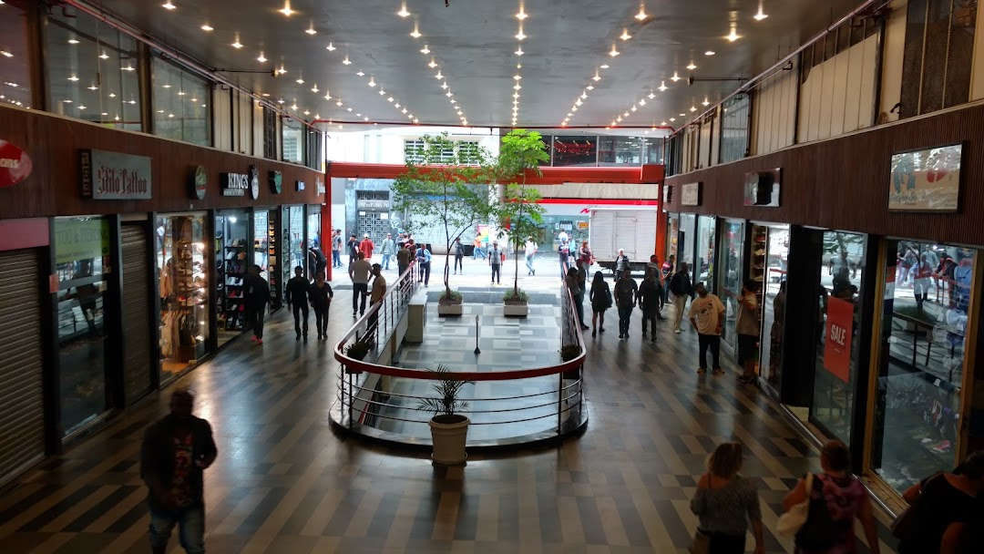 A bustling indoor shopping arcade with various shops and people walking through.