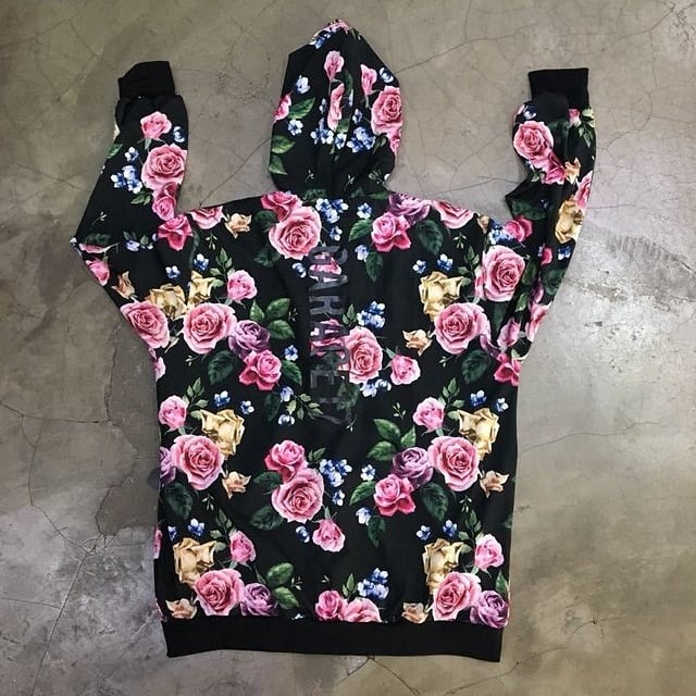 A black hoodie with a vibrant floral print featuring pink roses and blue flowers.
