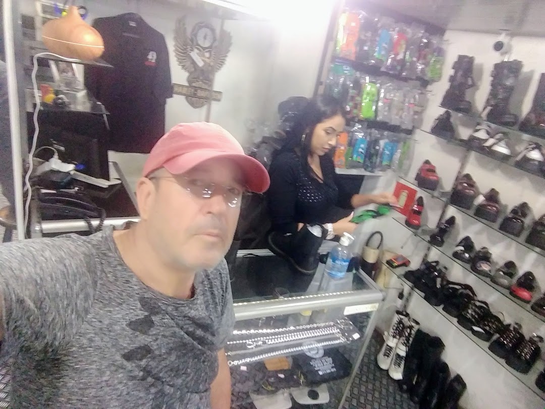 A man in a red cap poses in front of a shoe store with a woman behind the counter.