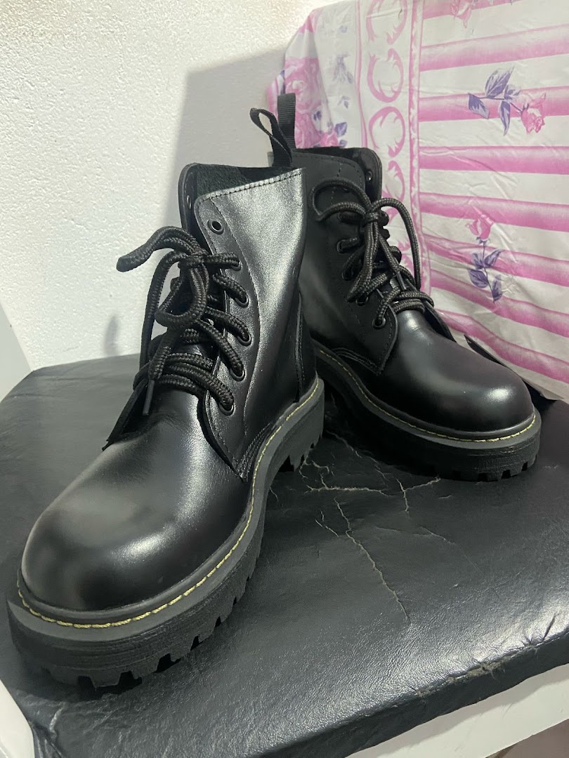 A pair of black lace-up boots with thick soles are displayed.