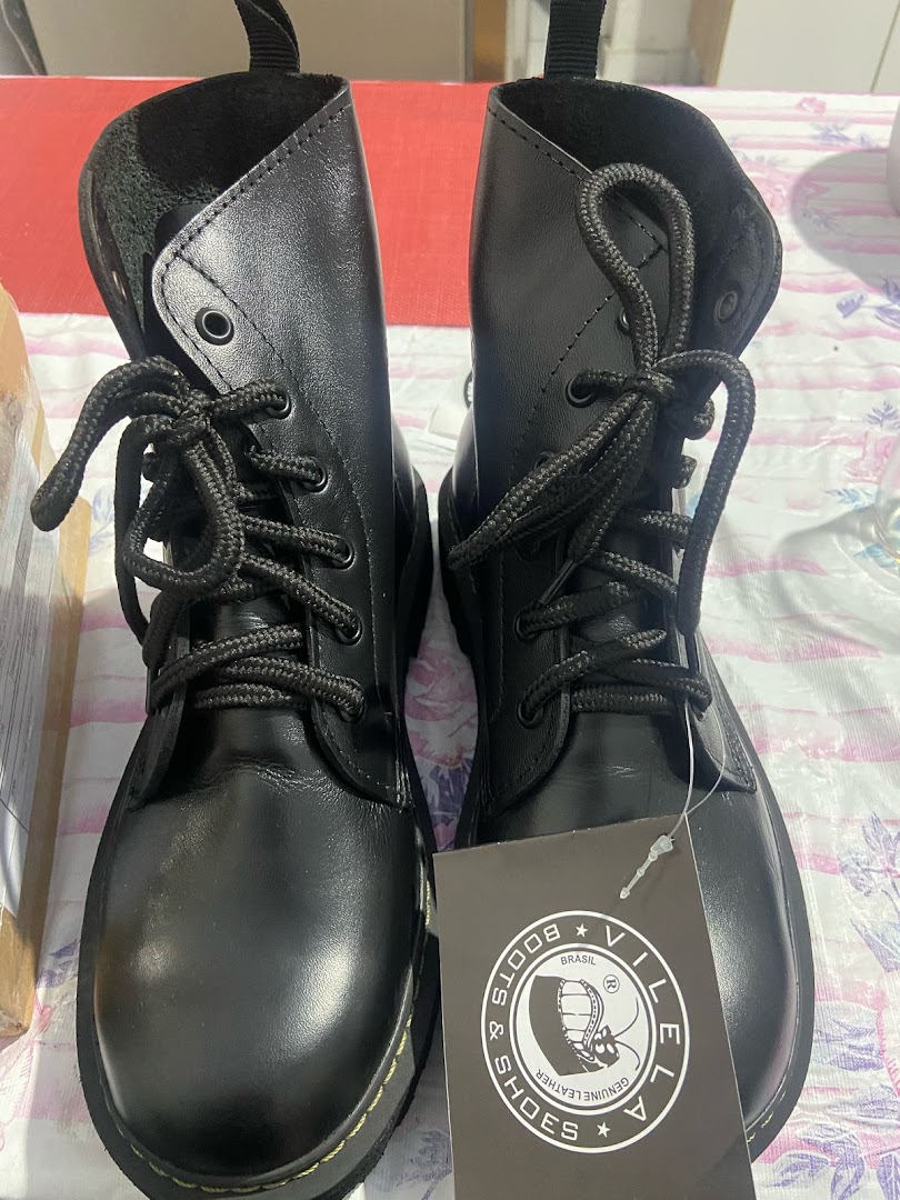 A pair of black leather lace-up boots from Vilela Boots with a branded tag.