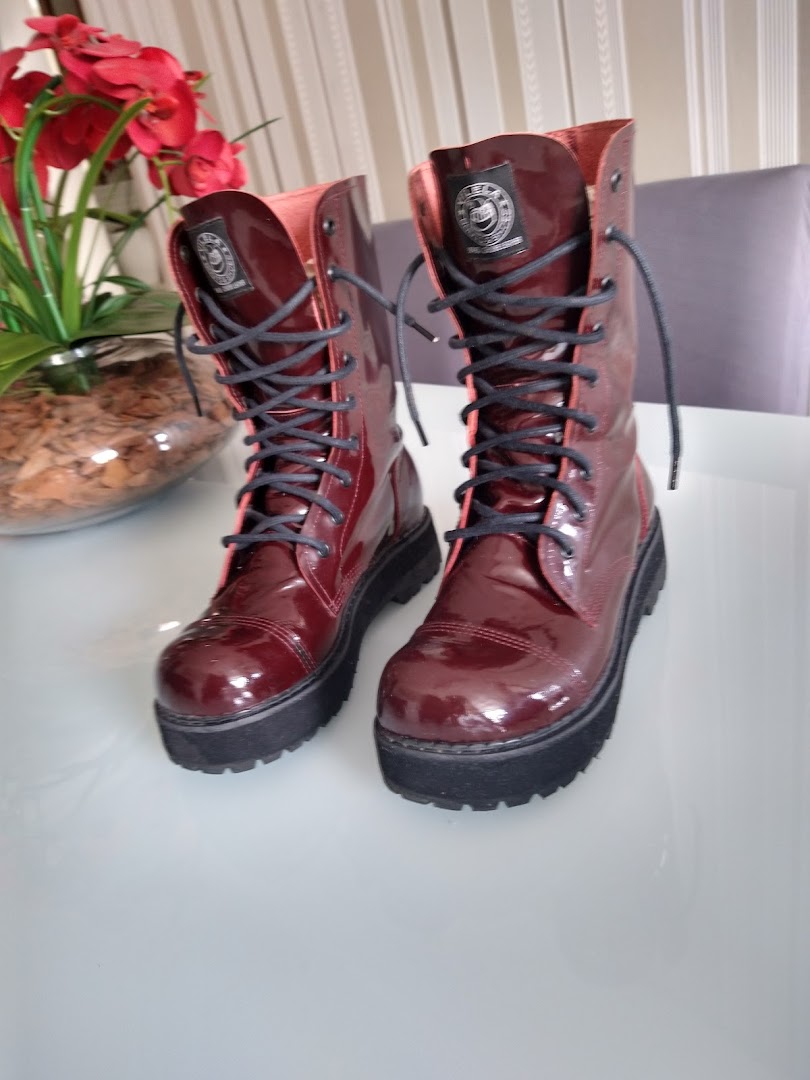 A pair of shiny, burgundy, lace-up boots with thick soles.
