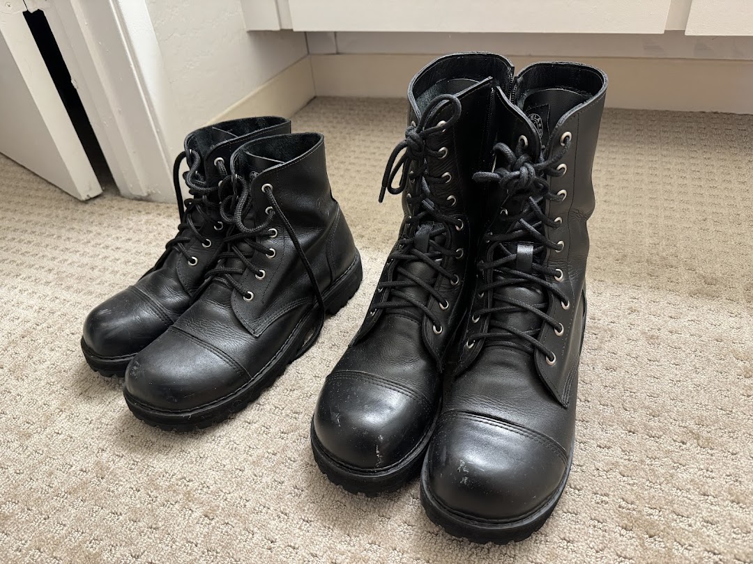 A pair of black leather lace-up boots and another pair of black leather boots.