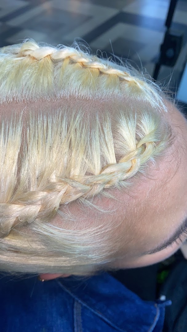 Close-up of a person's blonde hair being styled into intricate braids.