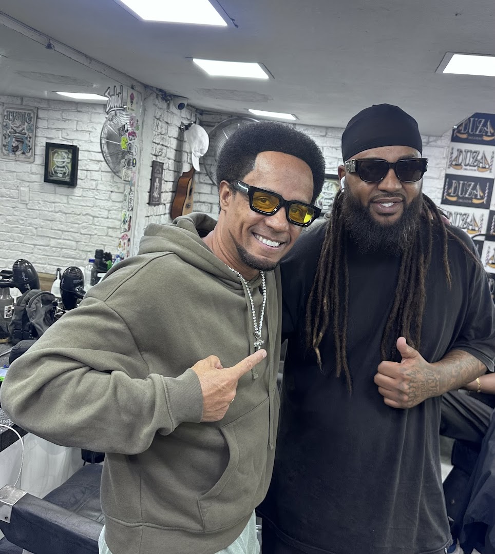 Two men posing for a photo inside a barbershop.