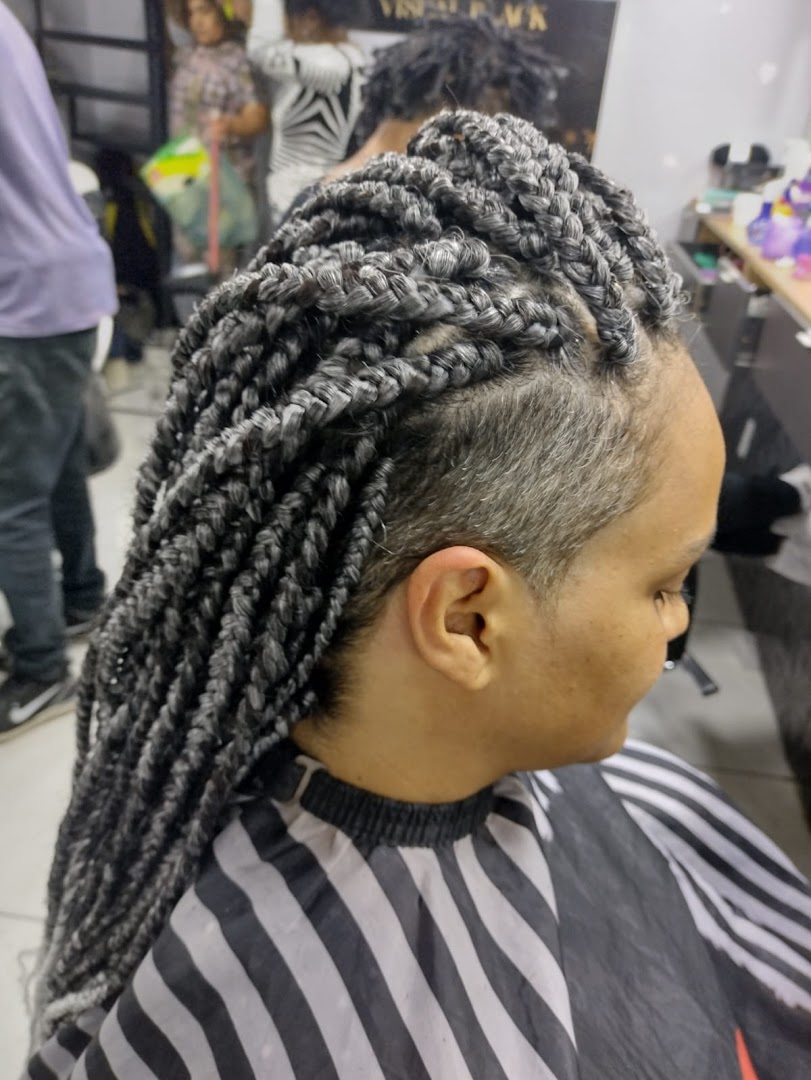 A woman with stylish grey box braids and an undercut hairstyle at a salon.