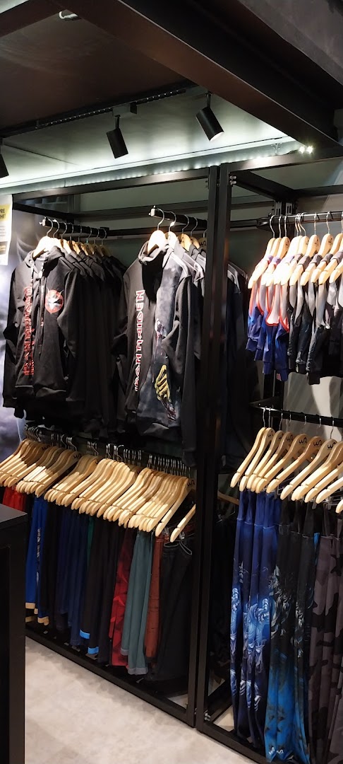 Interior view of a retail store displaying racks of clothing, including hoodies and pants.