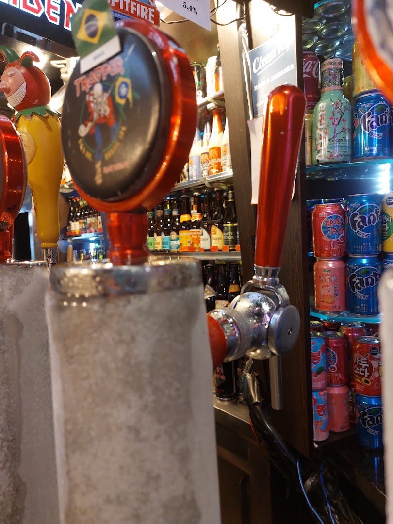 Close-up of beer taps and shelves stocked with various canned drinks and bottles.