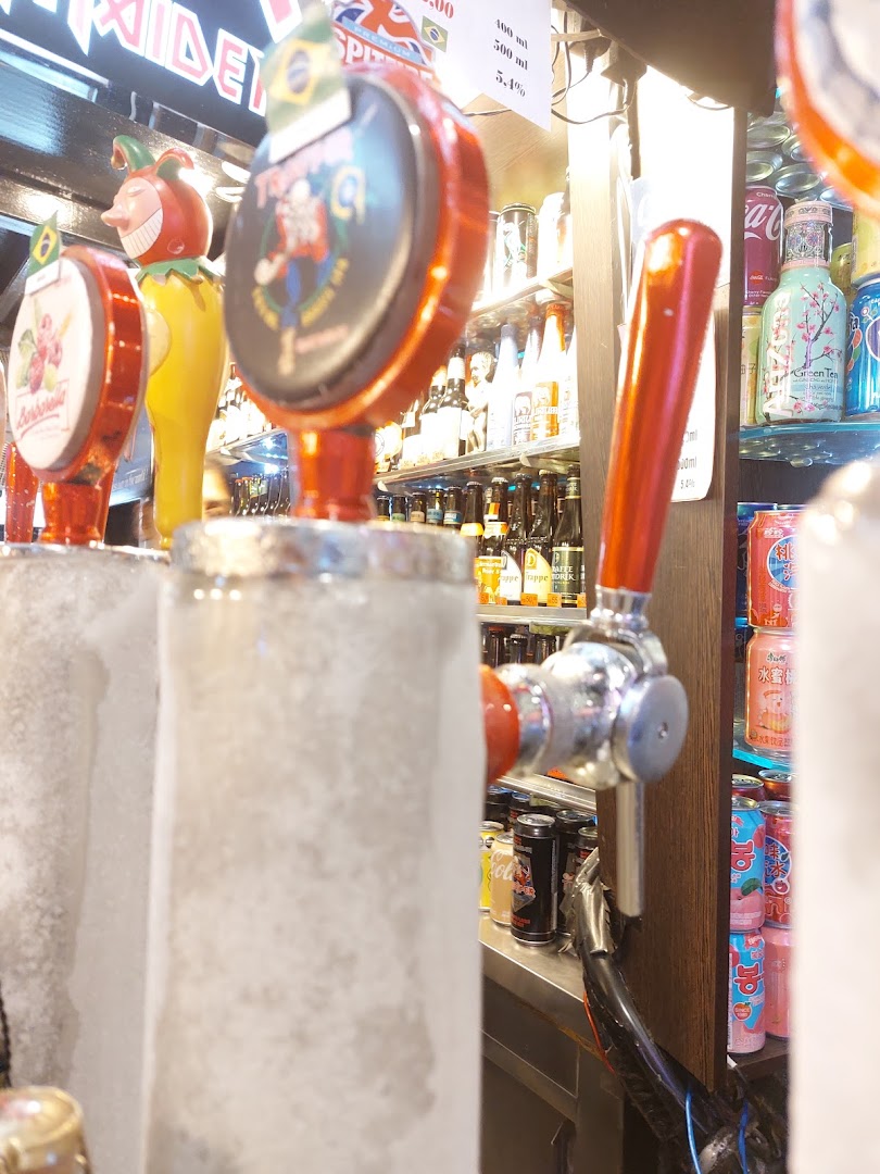 Close-up of beer taps with a selection of bottled drinks and cans in the background.