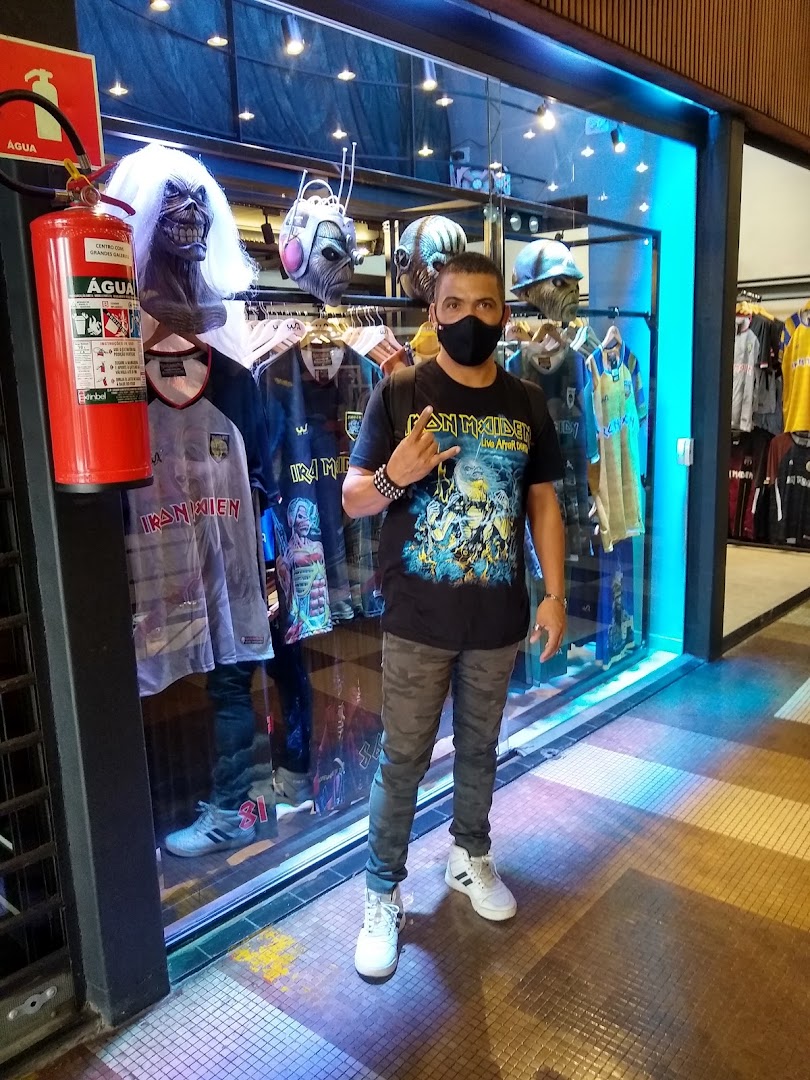A man stands in front of a shop window displaying Iron Maiden merchandise and mannequins.