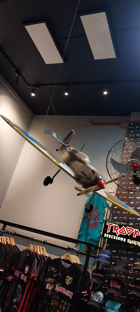 Interior of a shop with Iron Maiden merchandise and a model airplane hanging from the ceiling.