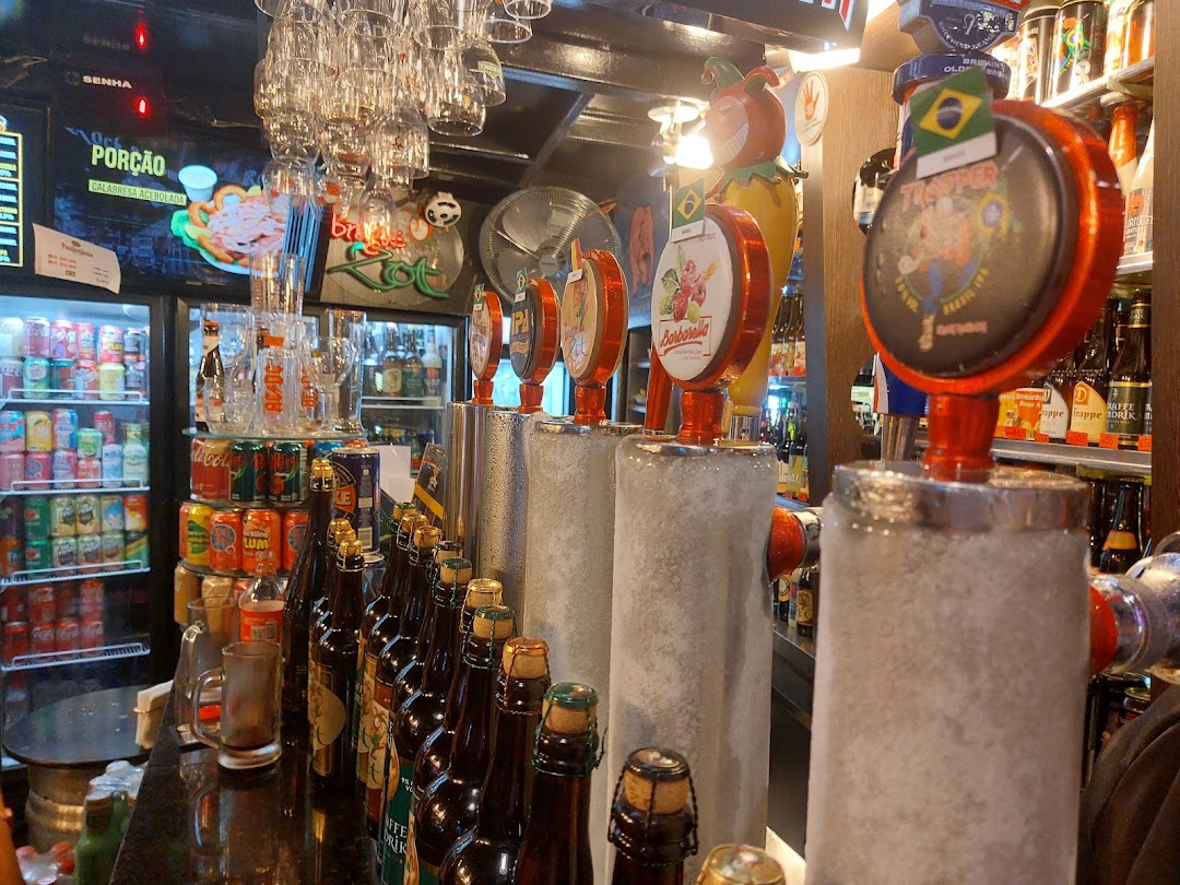A bar with beer taps, refrigerators stocked with drinks, and bottles on the counter.