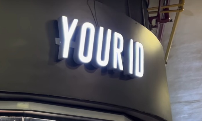 A close-up shot of the illuminated "YOUR ID" sign above a shop entrance.