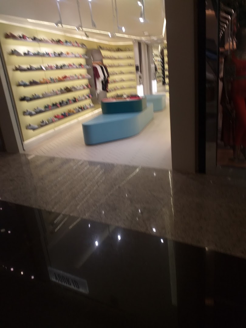 Interior view of a shoe store with shelves displaying various footwear and seating areas.