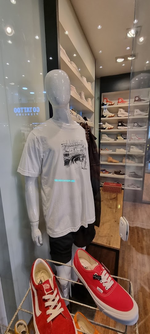 A mannequin displays a graphic t-shirt and shorts, with shelves of sneakers in the background.